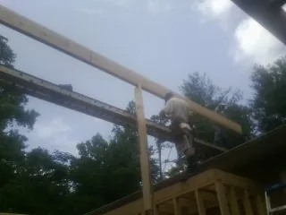 Carpenter setting a ridge beam over a new addition frame — Ice Dam Removal by Roofing Brothers in Guy