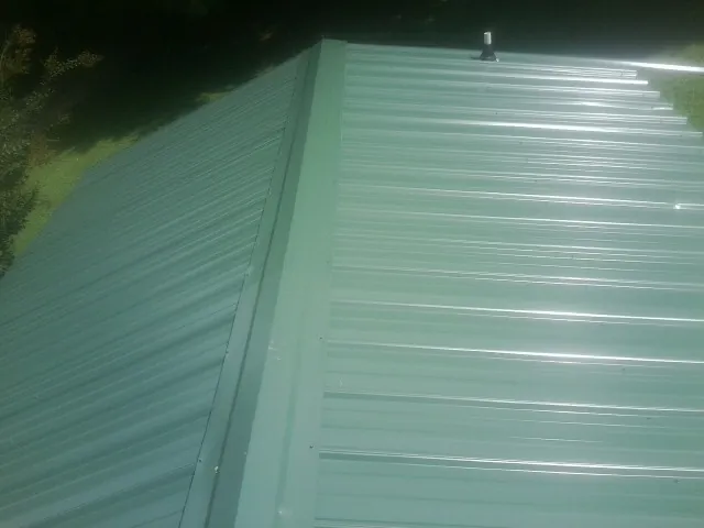 New green metal panels meeting at the ridge of a roof — Flat Roof Repair work by our crew in Guy