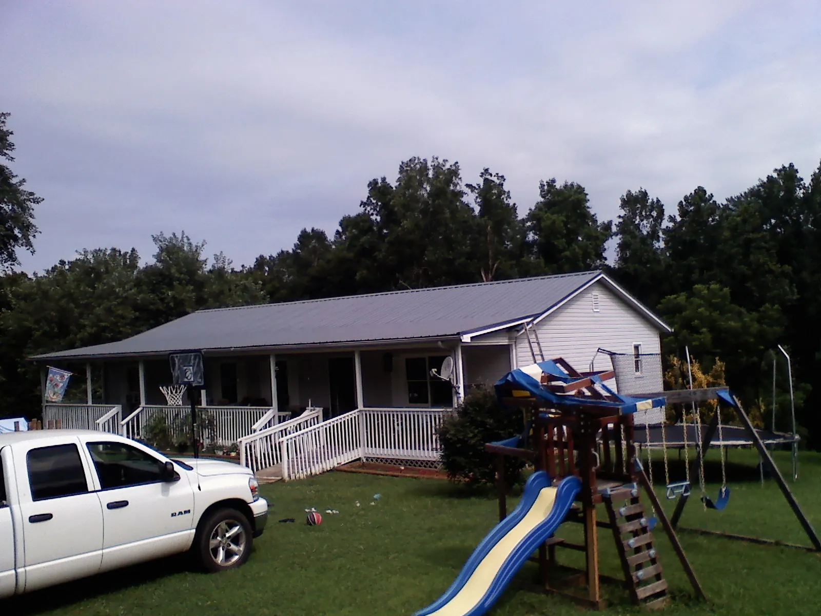 Dark metal roof on a country home with a full length front porch in Guy
