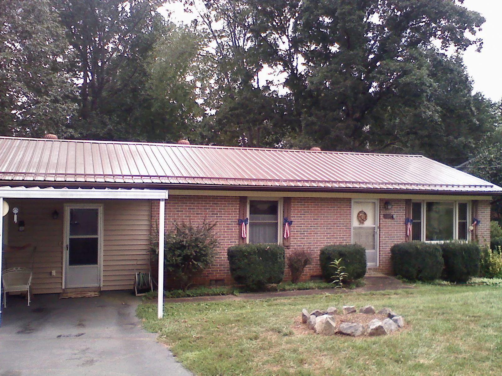 Bronze metal roof and carport on a brick ranch home — Roof Repair work by our crew in Guy