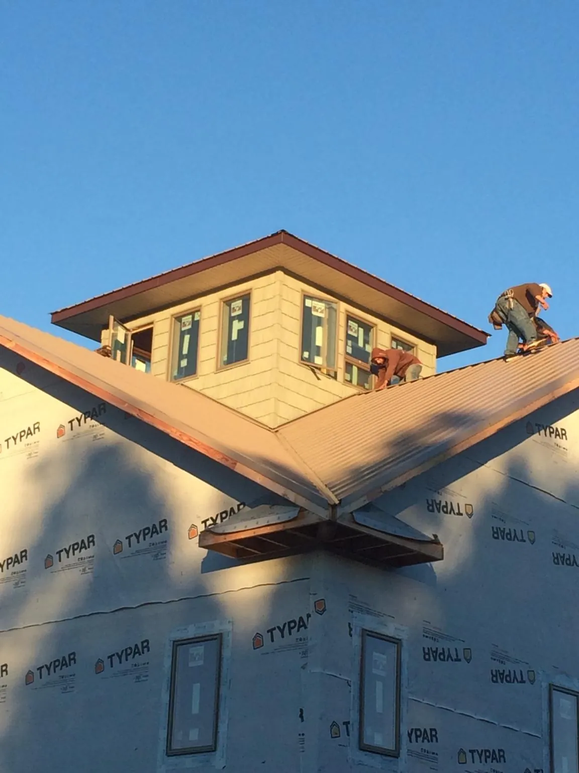 Roofers working around a rooftop cupola on a new metal roof at sunset — Roof Waterproofing in Guy by Roofing Brothers